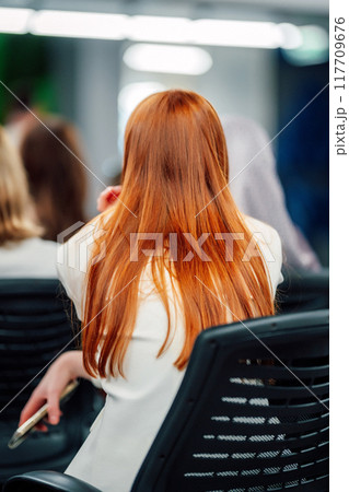 Photo of a woman with long beautiful hair sitting at a conference. groomed hair Photo of a woman with long beautiful hair sitting at a conference. groomed hair 117709676