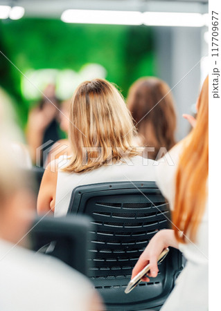 Photo of a woman with long beautiful hair sitting at a conference. groomed hair Photo of a woman with long beautiful hair sitting at a conference. groomed hair 117709677