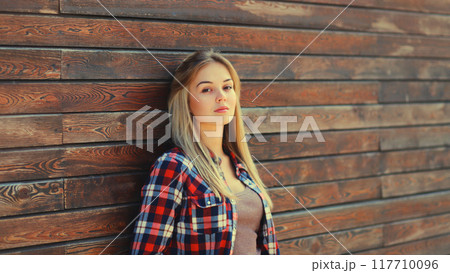 Portrait of beautiful caucasian blonde young woman in casual checkered shirt in the city Portrait of beautiful caucasian blonde young woman in casual checkered shirt in the city 117710096