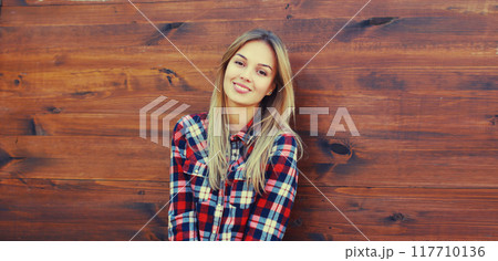 Portrait of beautiful caucasian blonde smiling young woman in casual checkered shirt in the city 117710136