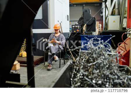 Worker in Factory Taking Break and Checking Smartphone 117710796