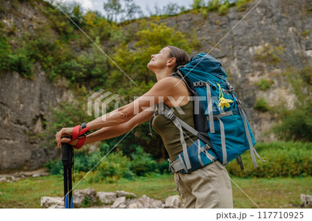 A Woman Enjoying Hiking in Nature While Carrying a Backpack and Using Trekking Poles A Woman Enjoying Hiking in Nature While Carrying a Backpack and Using Trekking Poles 117710925