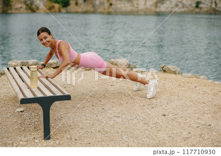 Outdoor Workout A Young Woman Exercising and Performing a Plank in the Fresh Air 117710930