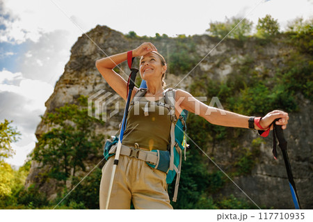 A hiker is enthusiastically enjoying the breathtaking beauty of nature in a scenic landscape 117710935