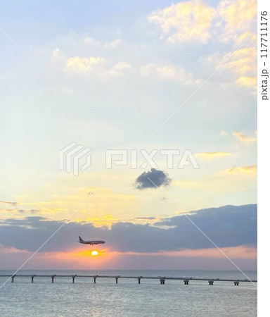 一機の飛行機が夕焼け中で、オーシャン上に浮かぶ空港に着陸 117711176