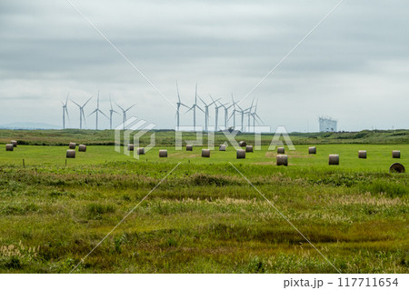 風力発電と牧草ロールのある風景 117711654