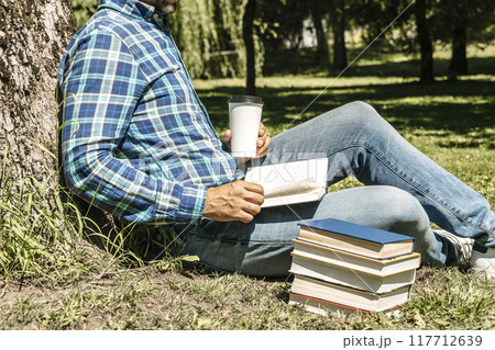 Reading a book. A young man reads a book or a textbook. Education, leisure, business concept. Reading a book. A young man reads a book or a textbook. Education, leisure, business concept. 117712639