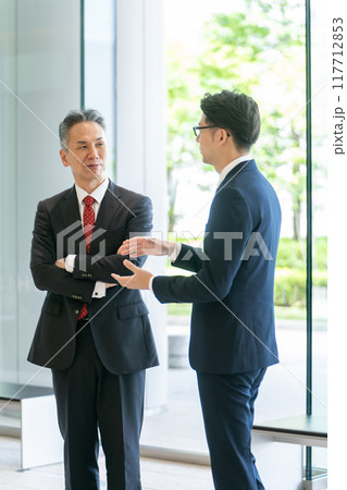 オフィスのロビーで会話する上司と部下 オフィスのロビーで会話する上司と部下 117712853