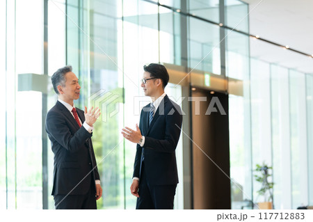 オフィスのロビーで会話する上司と部下 オフィスのロビーで会話する上司と部下 117712883