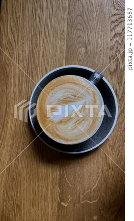 Coffee on a wooden counter with latte art in the shape of a leaf. 117713687