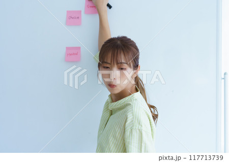 オフィスで課題を見える化する若い女性 117713739