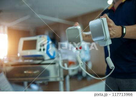 A person is holding a defibrillator in a hospital room A person is holding a defibrillator in a hospital room 117713966