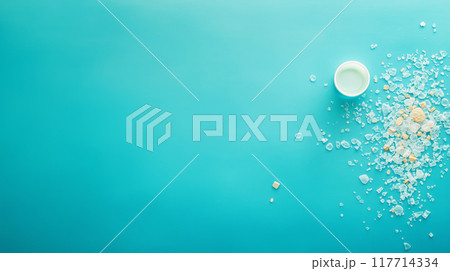 Small pieces of shattered plastic scattered on light blue background, emphasizing plastic pollution 117714334