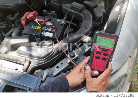 Technician diagnosing old battery health of automobile with instrument. Test result suggested battery is weak with 9 percent health. Technician diagnosing old battery health of automobile with instrument. Test result suggested battery is weak with 9 percent health. 117715199