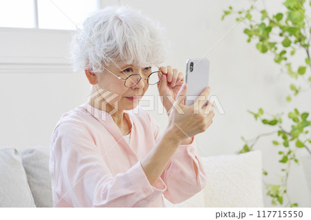 スマートフォンを見る老眼のシニア女性 117715550