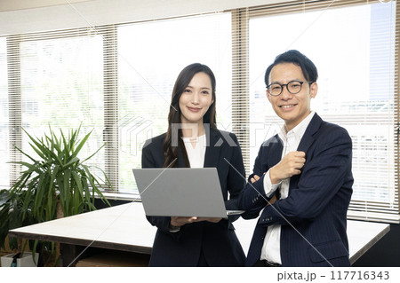 社内で打ち合わせをする男性社員と女性社員 社内で打ち合わせをする男性社員と女性社員 117716343