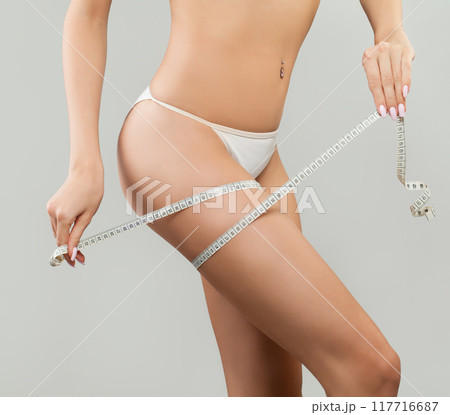 Woman measuring her leg on a white studio background. Perfect Slim Body  117716687