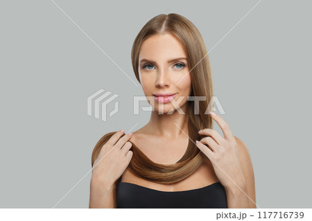Healthy woman face. Model with long brown hair and make-up on grey background. 117716739