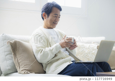 リビングでノートパソコンを使うミドル男性 117716949