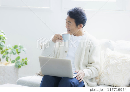 リビングでノートパソコンを使うミドル男性 リビングでノートパソコンを使うミドル男性 117716954