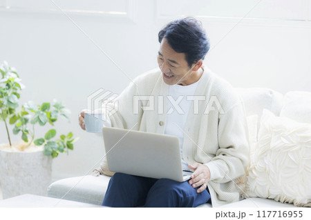 リビングでノートパソコンを使うミドル男性 リビングでノートパソコンを使うミドル男性 117716955