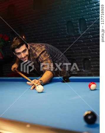 Man trying to hit the ball in billiard at room pool at bar. 117716989