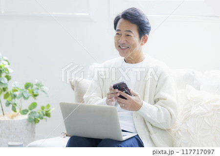 リビングでノートパソコンを使うミドル男性 リビングでノートパソコンを使うミドル男性 117717097