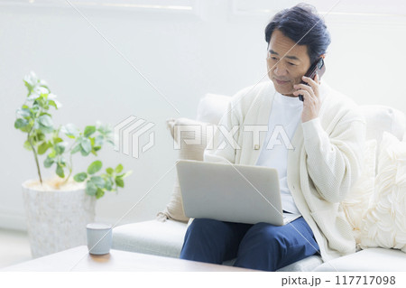 リビングでノートパソコンを使うミドル男性 リビングでノートパソコンを使うミドル男性 117717098