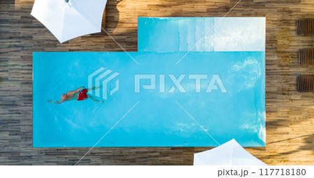 Luxury Villa Pool with Man Swimming Alone from Above. Concept of relaxation and privacy in a high-end property 117718180