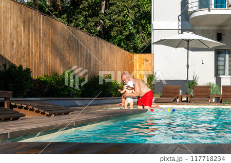 Father with little toddler girl in swimming pool in modern villa at sunset 117718234
