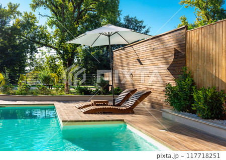 Stylish Swimming Pool in Modern Villa with Palm Trees and Lounge Chairs. Concept of comfort and elegance in a luxury space Stylish Swimming Pool in Modern Villa with Palm Trees and Lounge Chairs. Concept of comfort and elegance in a luxury space 117718251