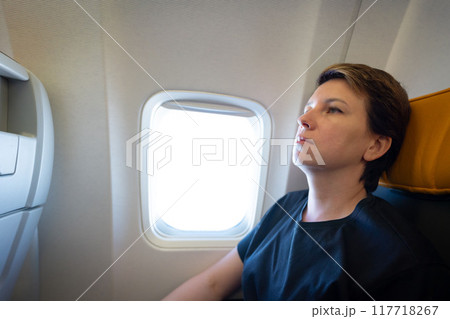 Young tired and sad woman on a plane. Travel, vacations, holiday and tourism concept 117718267