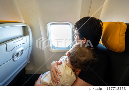 A Loving Mother Holding Her Precious Baby While Seated by the Airplane Window During Their Flight 117718358