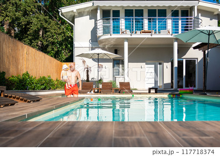 Father with little toddler girl in swimming pool on sunny day in modern villa Father with little toddler girl in swimming pool on sunny day in modern villa 117718374