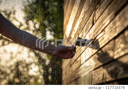 Female hand opens outdoor shower faucet at sunset. Concept of summer fun and relaxation with flowing water Female hand opens outdoor shower faucet at sunset. Concept of summer fun and relaxation with flowing water 117718379