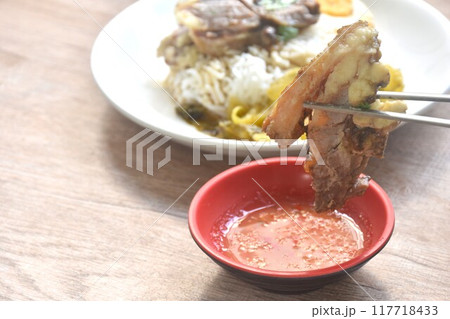 chopsticks picking braised  slice beef stew black Chinese herb soup  dipping spicy sour chili sauce on cup 117718433