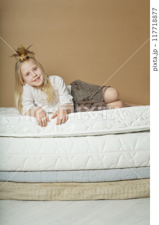 Happy pretty blonde child girl lying on bed, indoor portrait 117718877