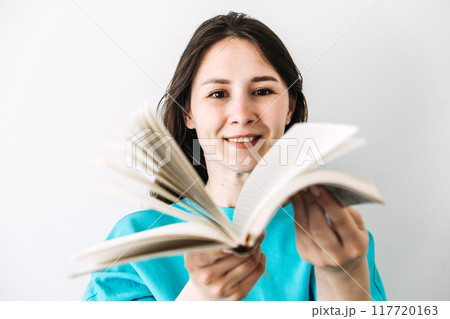 Woman smiling while holding an open book, symbolizing education, empowerment, and gender equality. 117720163