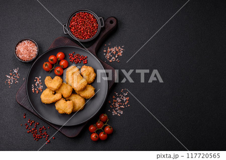 Delicious fresh crispy chicken nuggets on a dark concrete background 117720565