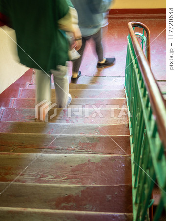 people go down wooden steps of apartment building 117720638