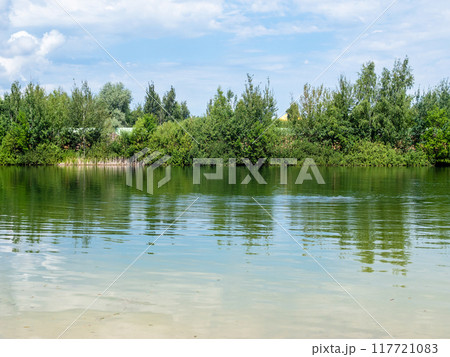 village pond with green bank on sunny summer day 117721083