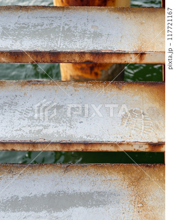 footprint on step of metal pier staircase close up 117721167