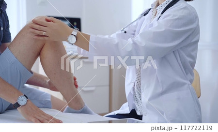 Doctor is carefully examining a patient's knee, providing personalized care and support. Medicine and orthopedic concept 117722119