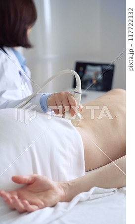 Doctor performing ultrasound examination on patient's back 117722132