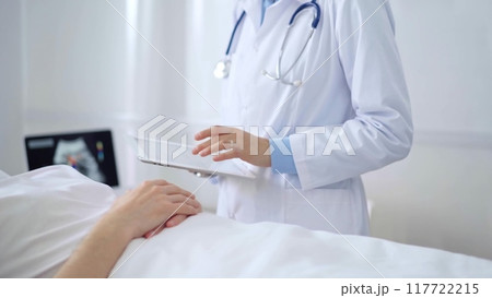Doctor consulting patient with digital tablet in hospital room. Healthcare professional providing care Doctor consulting patient with digital tablet in hospital room. Healthcare professional providing care 117722215