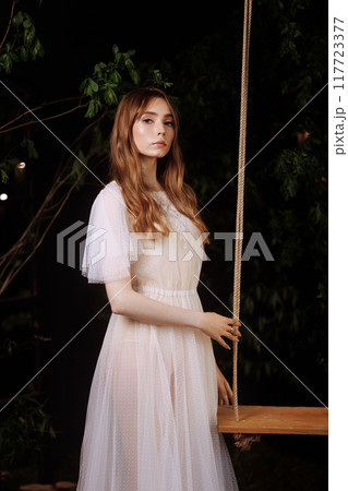 Elegant woman on wooden swing. 117723377