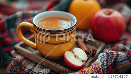 Close-up of yellow mug of hot drink with spices and cinnamon stick 117724397
