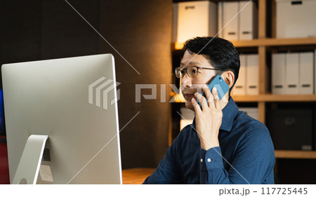 パソコンに向かって電話するミドル男性 パソコンに向かって電話するミドル男性 117725445