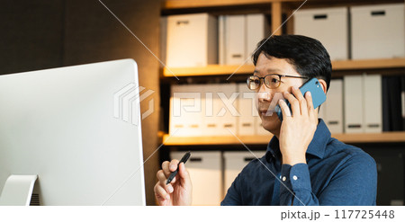 パソコンに向かって電話するミドル男性 パソコンに向かって電話するミドル男性 117725448