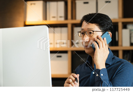 パソコンに向かって電話するミドル男性 パソコンに向かって電話するミドル男性 117725449